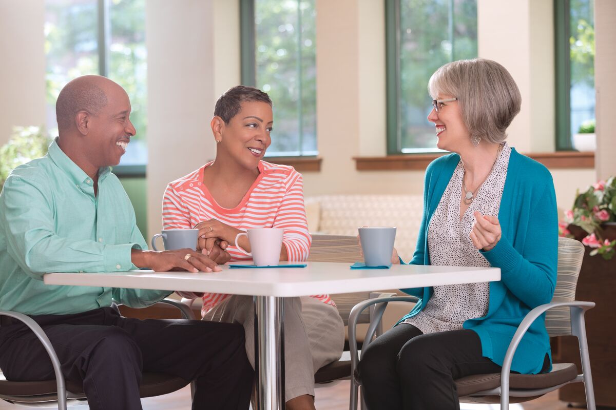 memory fitness Three seniors sit at a table with coffee laughing and talking