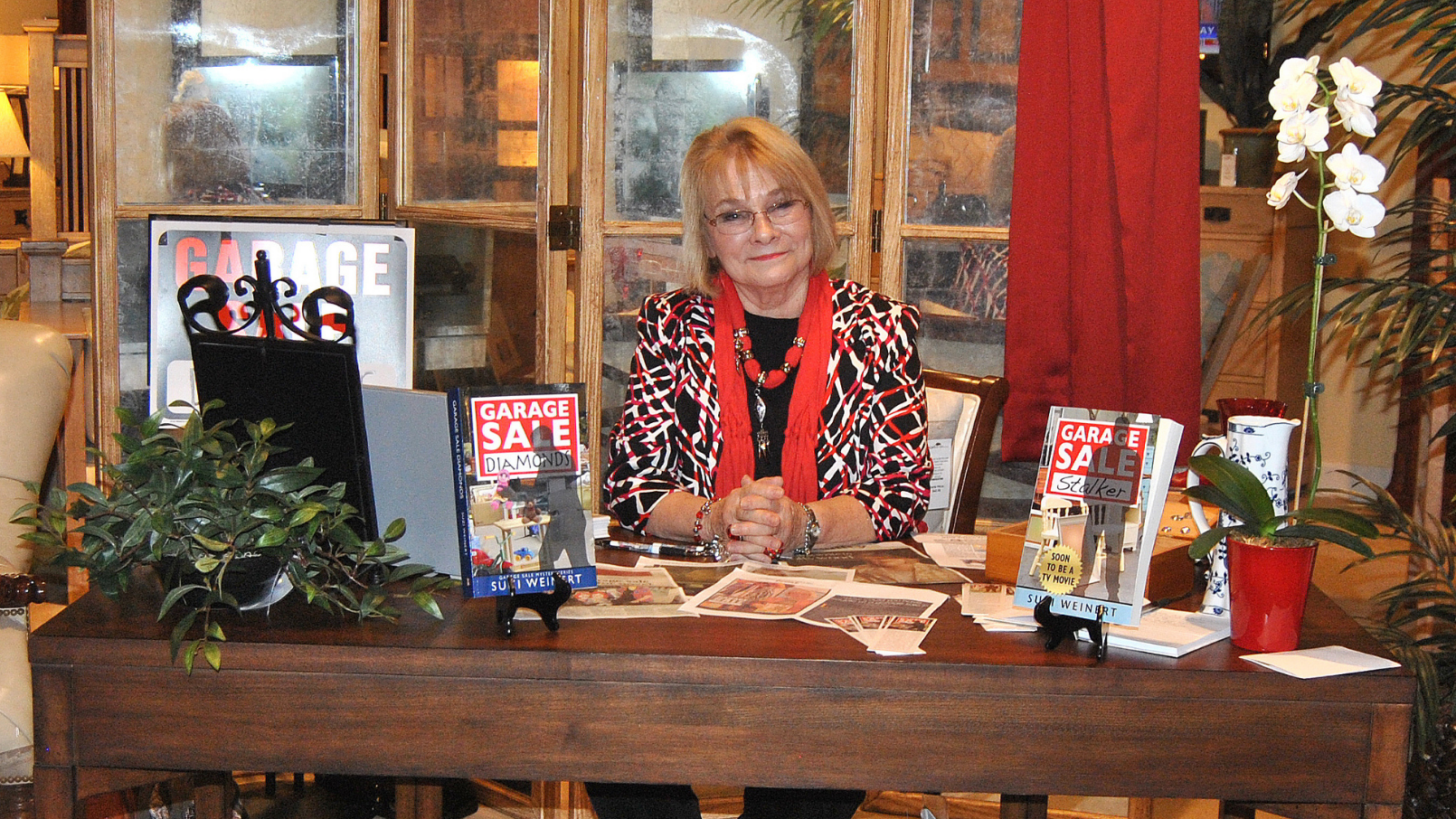 author Suzi Weinert.png author Suzi Weinert sitting at a desk with her novels