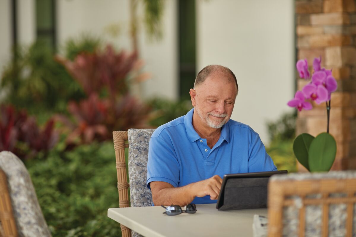 Devonshire community members enjoy continuing education Senior living resident uses tablet while sitting outside