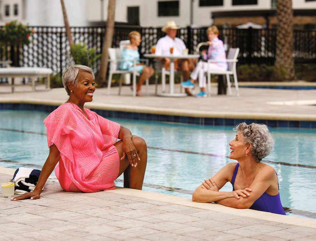 Two women talking at the edge of a swimming pool.