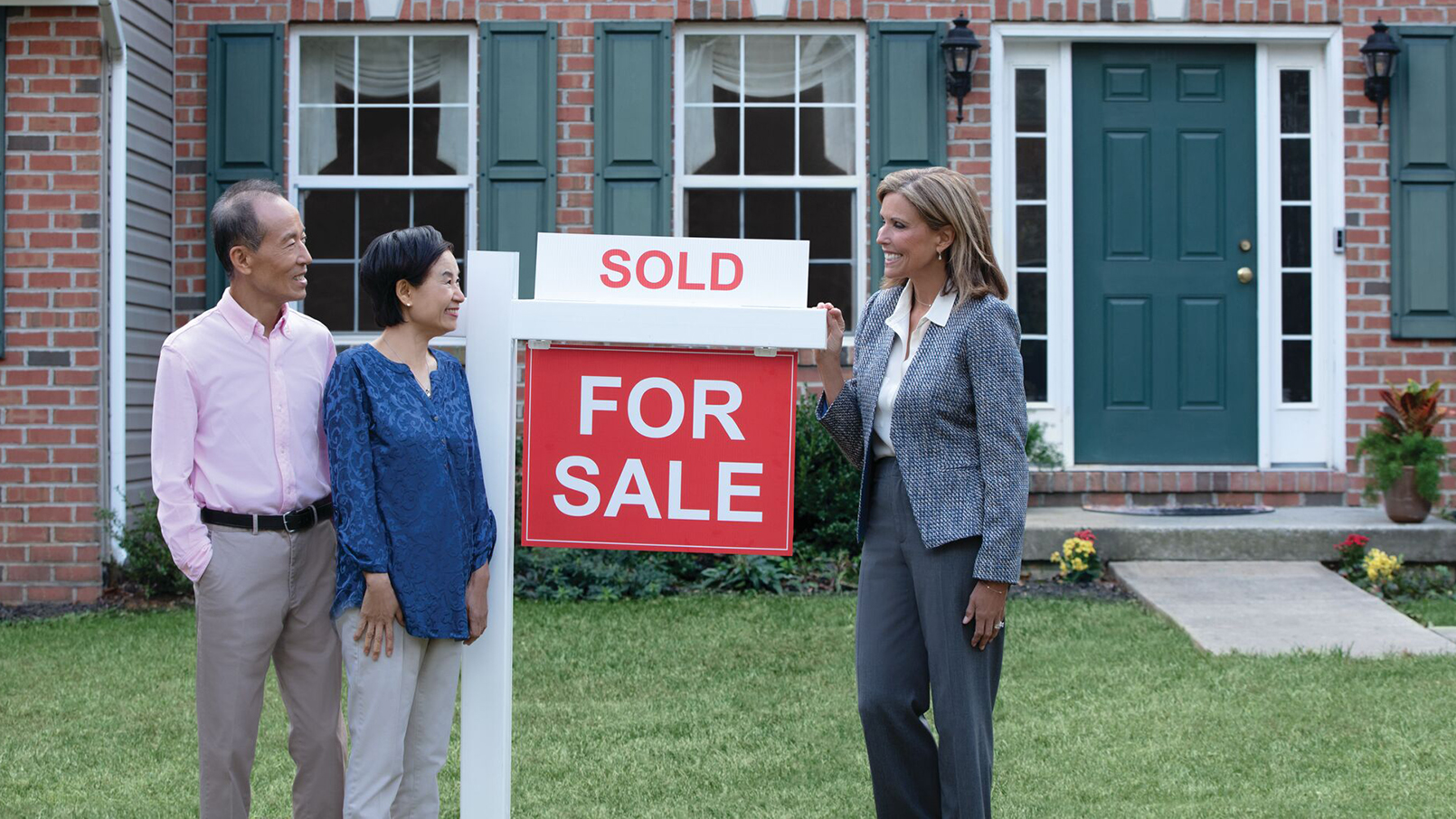 Couple with real estate agent and Sold sign