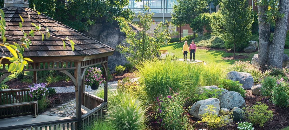 Couple takes a walk through a garden with gazebo on the Cedar Crest campus.