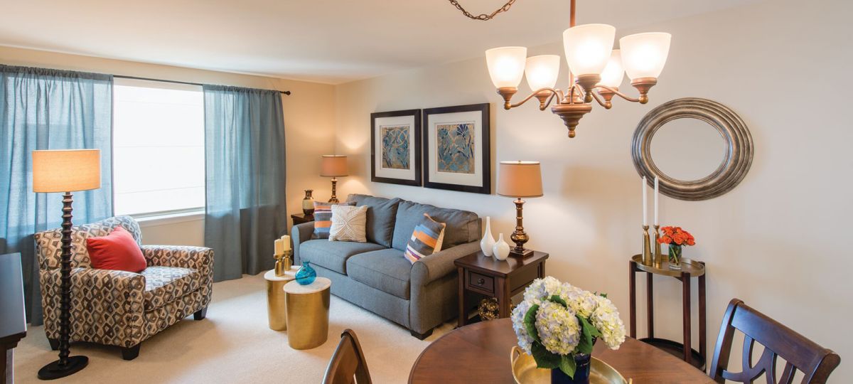 Living room with green couch, hanging lamps and round dining table.