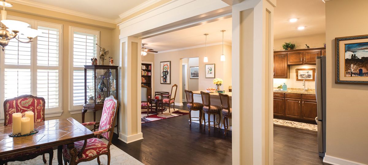 Stately open concept floor with decorative molding and dark wooden floors.