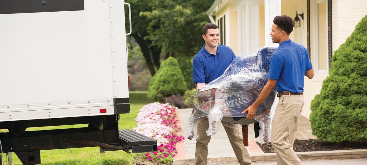 Two young men move a box into the back of a moving truck