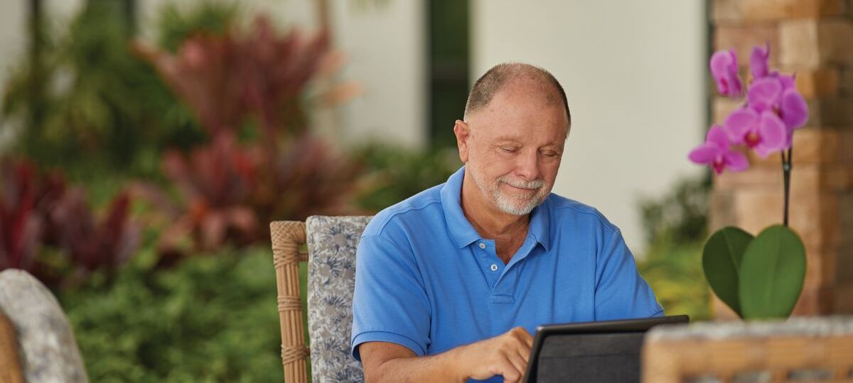 Senior living resident uses tablet while sitting outside