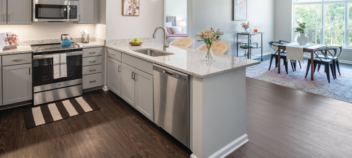 Interior shot of a bright kitchen with sit in dining area in the Maplewood apartment.