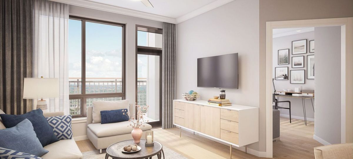 Wide shot of a nicely decorated, modern living room with balcony views of downtown Bethesda.