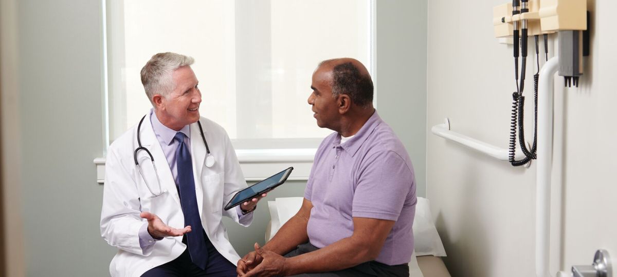 An Erickson physician talks with a patient in a campus medical practice examination room. 