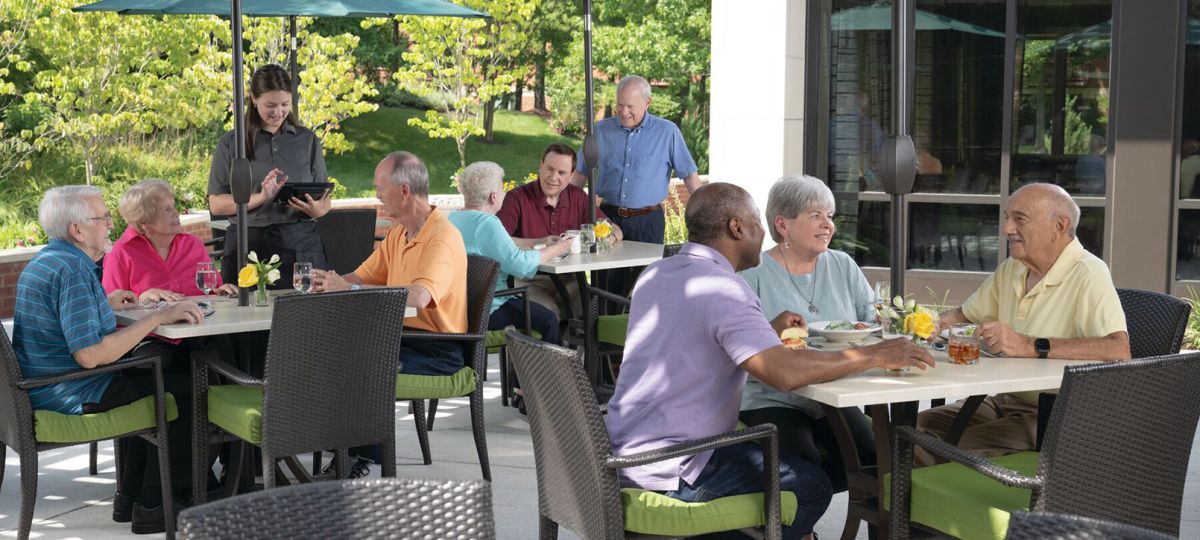 Residents savoring a meal together in the fresh air of our senior living community's outdoor dining area.