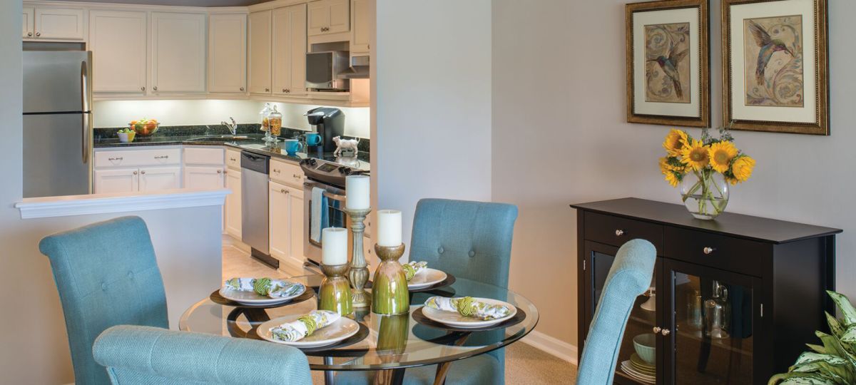 A modern senior apartment kitchen designed for accessibility with lowered countertops, ample lighting, easy-grasp cabinet handles, and a central island with seating.
