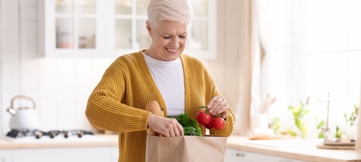 woman happily looking at full grocery bag