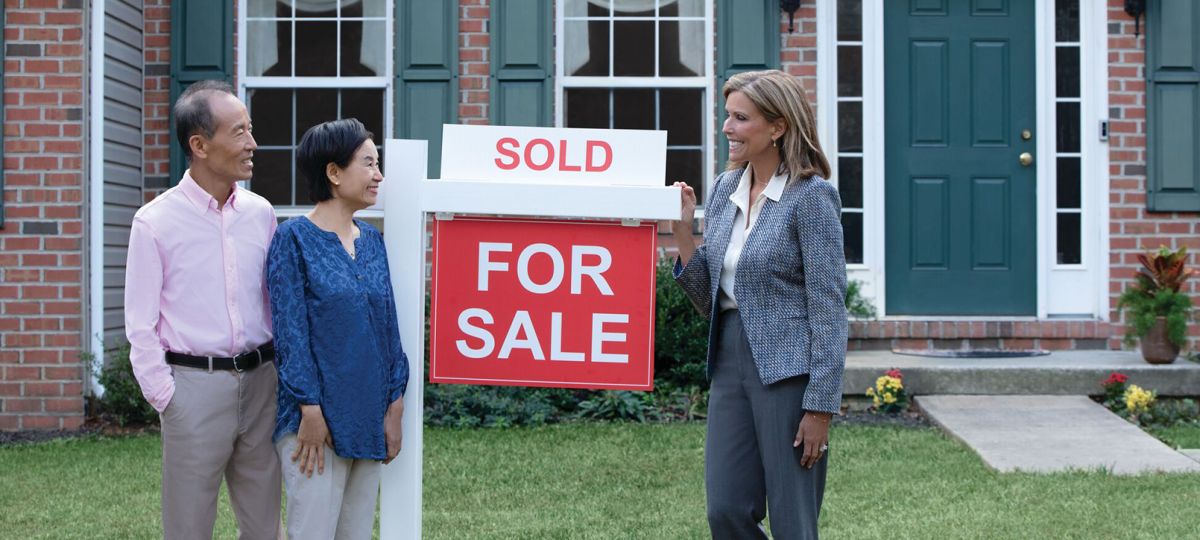 Couple with real estate agent and Sold sign