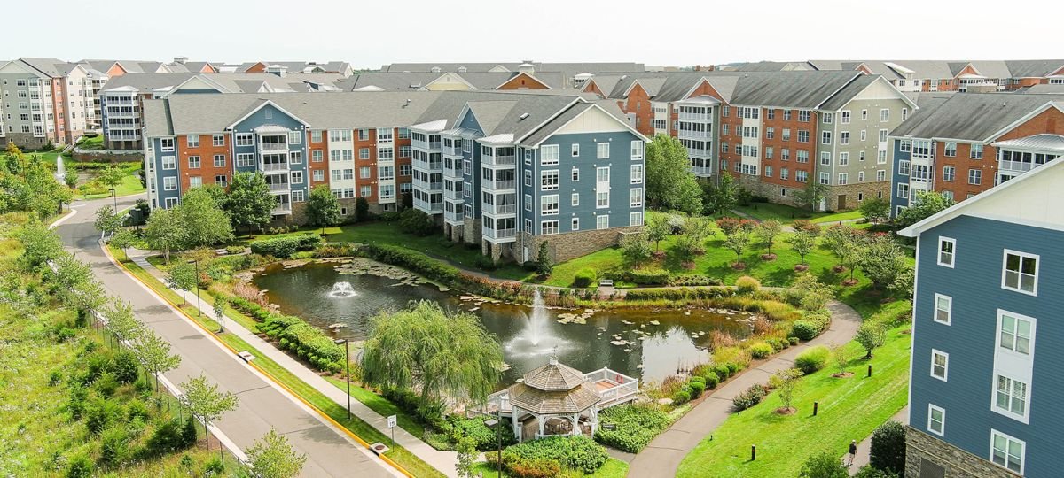 Aerial exterior shot of Ashby Ponds community buildings and surrounding greenery and pond.