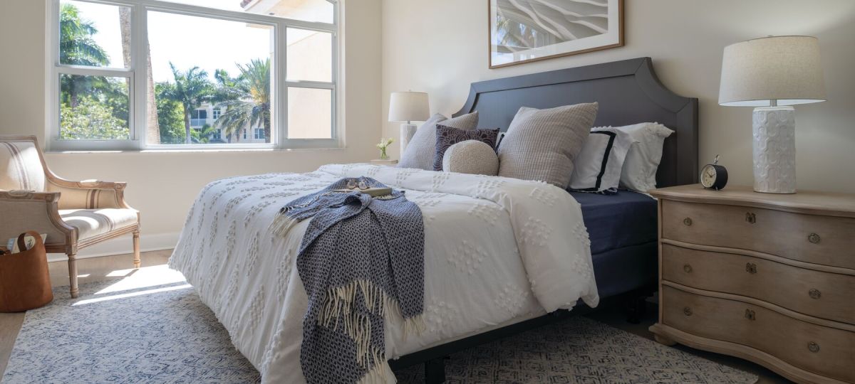 Cozy and spacious main bedroom with a large bed and open window inside of an Erickson Senior Living community apartment.