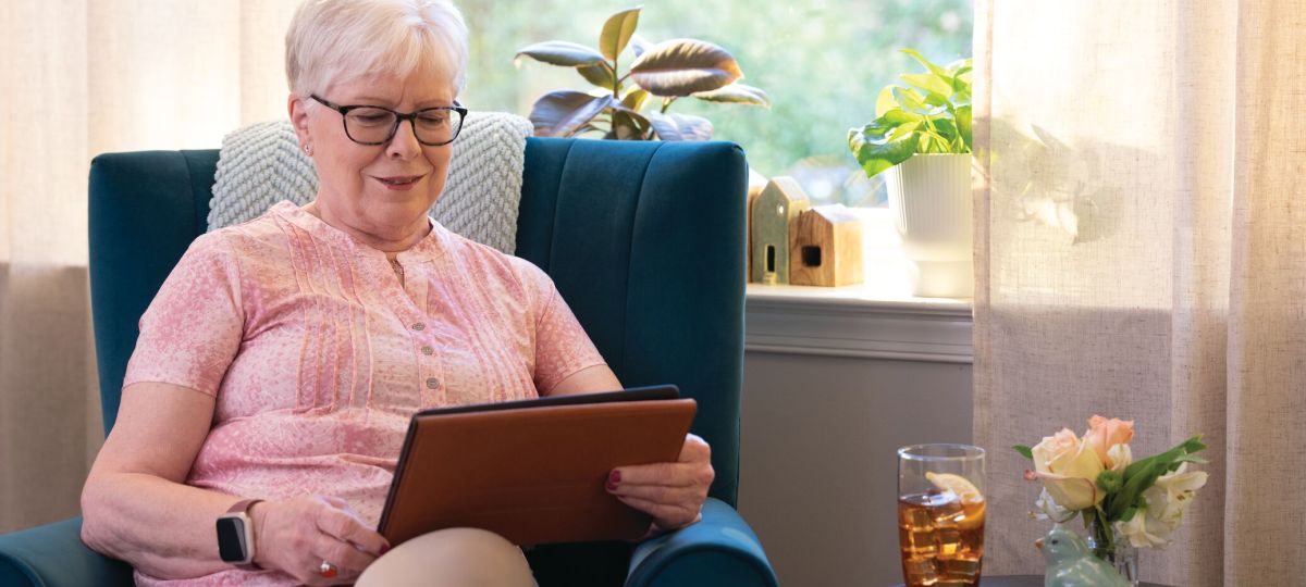 a woman sitting in a chair inside reading on a tablet