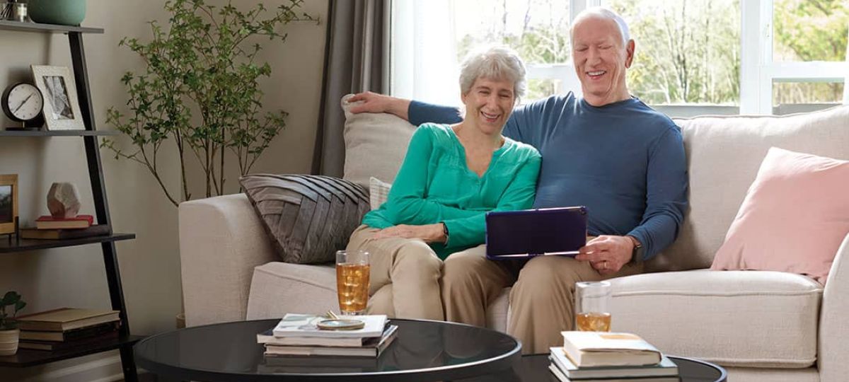 Couple sitting on couch watching a tablet computer