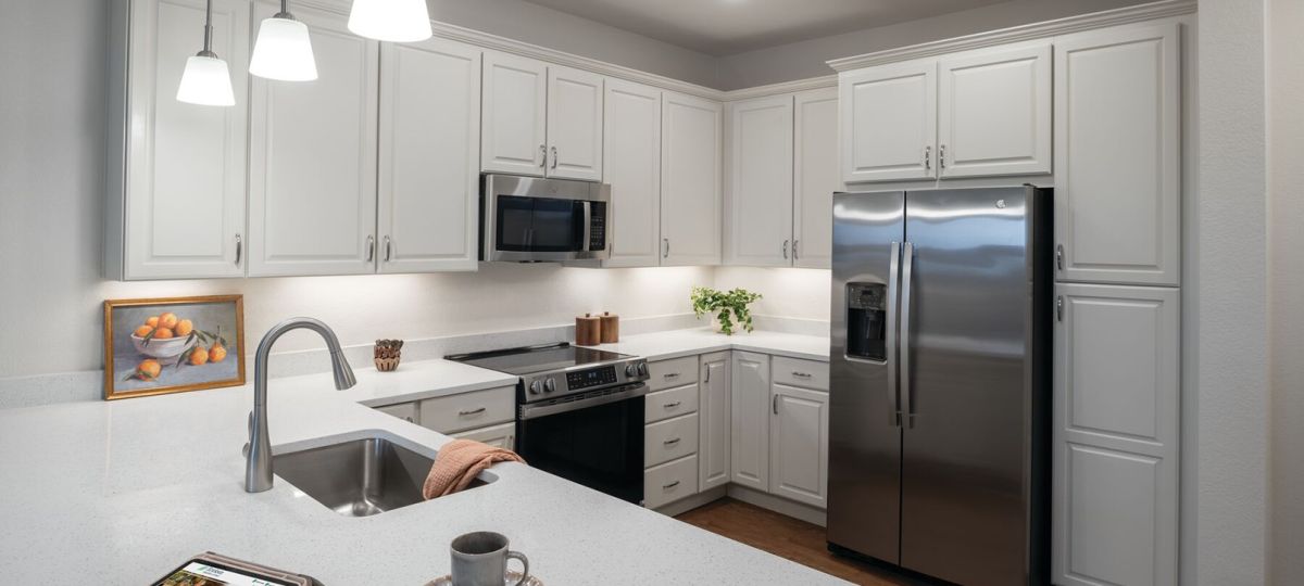 Modern kitchen with white cabinets, stainless steel appliances, quartz countertops, and pendant lighting.