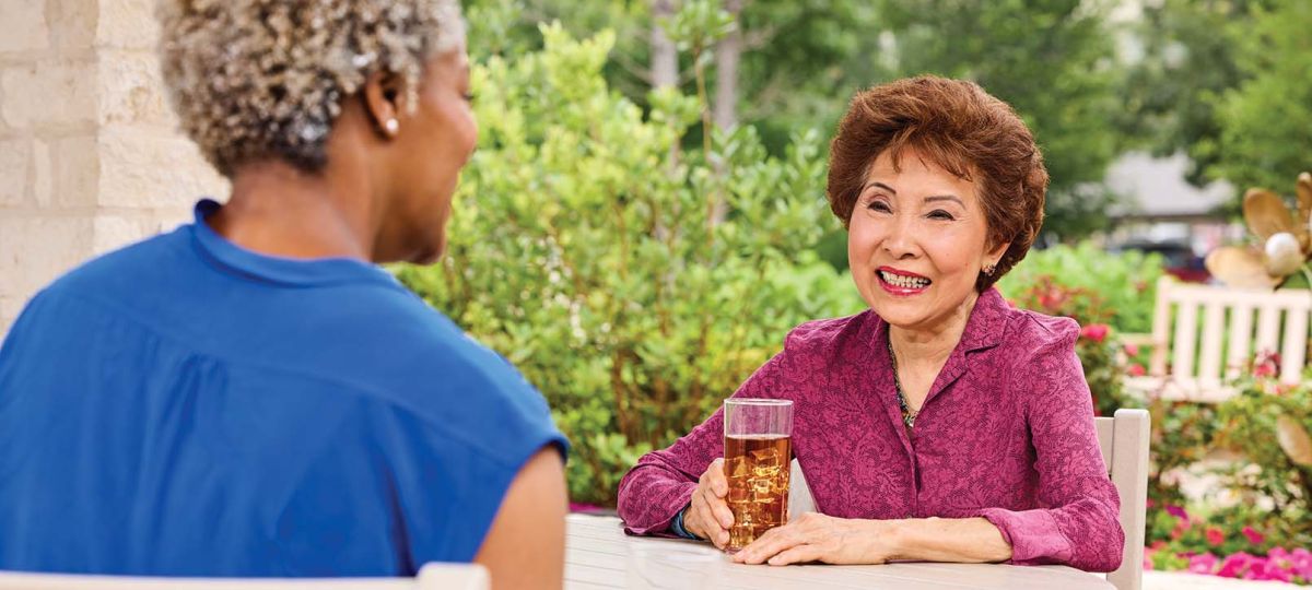 2 residents talking outside with drinks