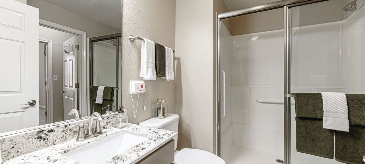 Modern bathroom with granite vanity countertop, walk-in glass shower, and neutral finishes.
