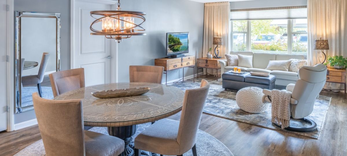 Elegant open-concept dining and living room with modern lighting, wood flooring, and large windows.