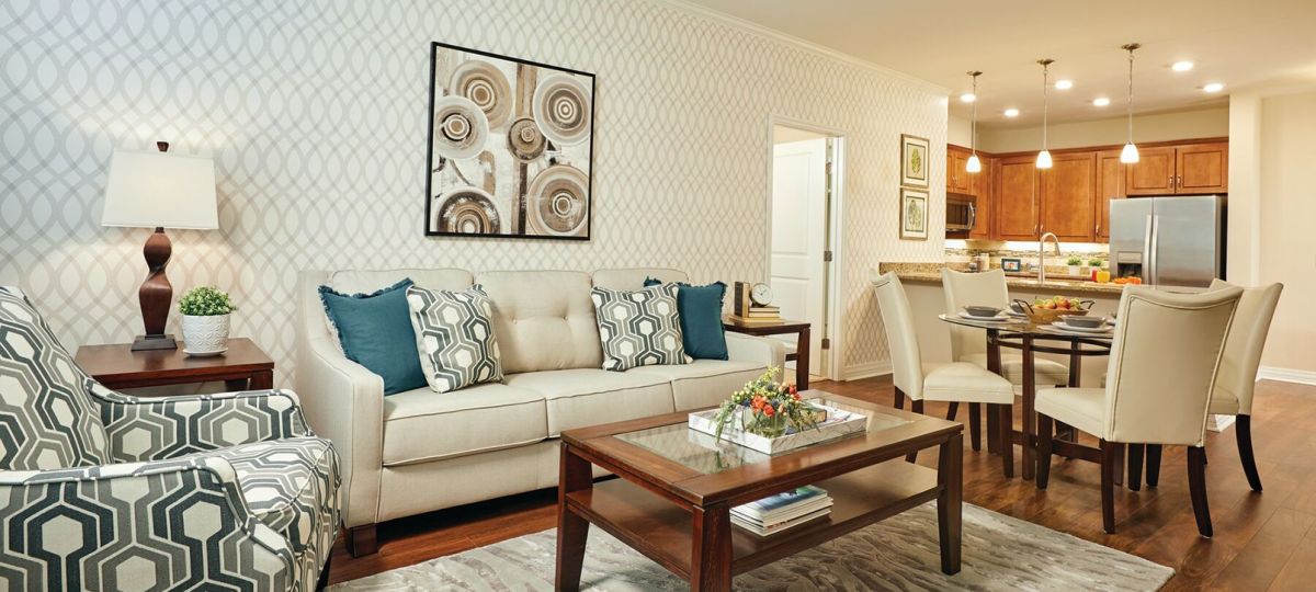 Stylish open-concept living and dining room with patterned accent chairs, wood flooring, and adjacent kitchen.
