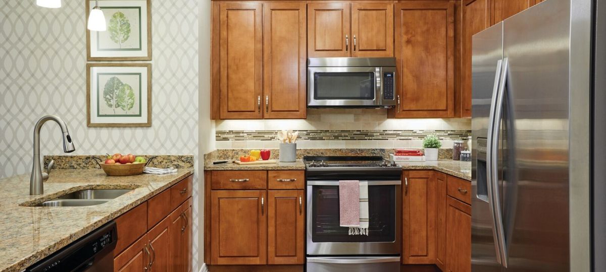 Modern kitchen with wood cabinetry, granite countertops, stainless steel appliances, and pendant lighting.