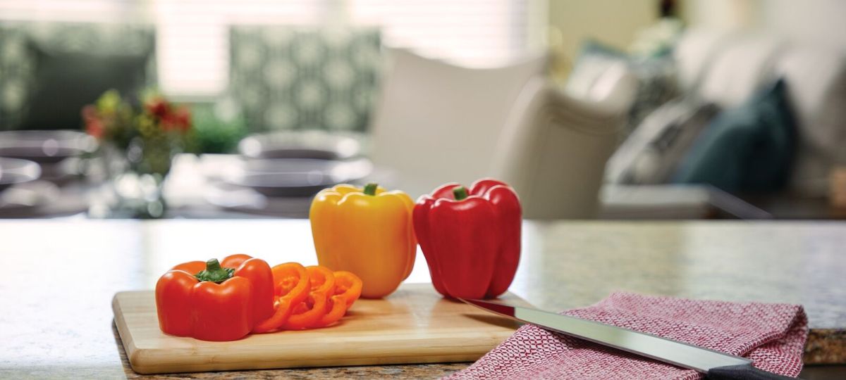 Fresh bell peppers on a kitchen countertop with modern open-concept living area in the background.