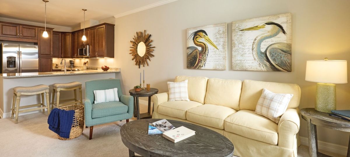 Spacious open-concept living room with cream sofa, accent chairs, and modern kitchen with granite countertops and stainless-steel appliances.