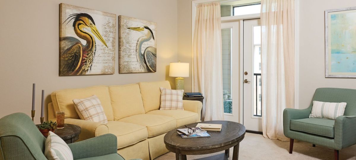 Cozy living room with soft neutral decor, accent seating, and balcony access through glass doors.