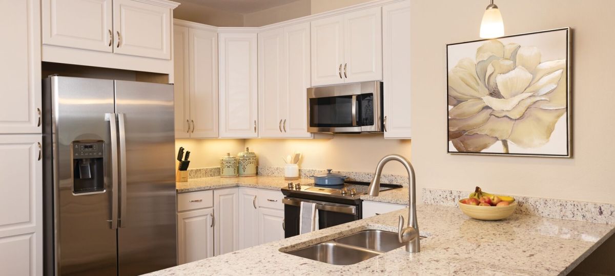 Bright kitchen with white cabinetry, granite countertops, stainless steel appliances, and pendant lighting.