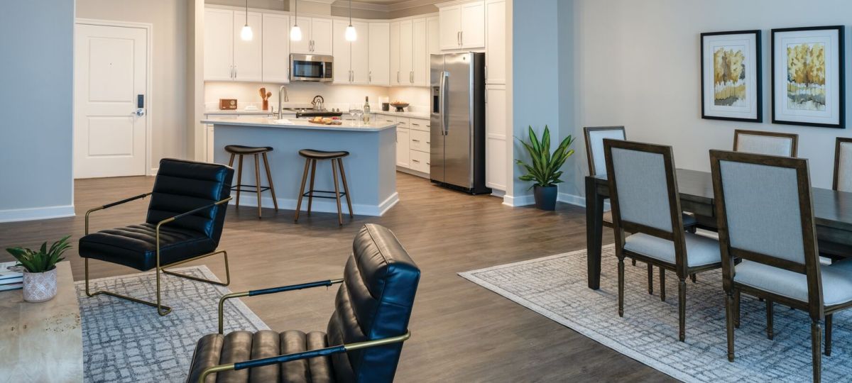 Modern open-concept apartment with dining area, contemporary seating, and bright white kitchen with island.