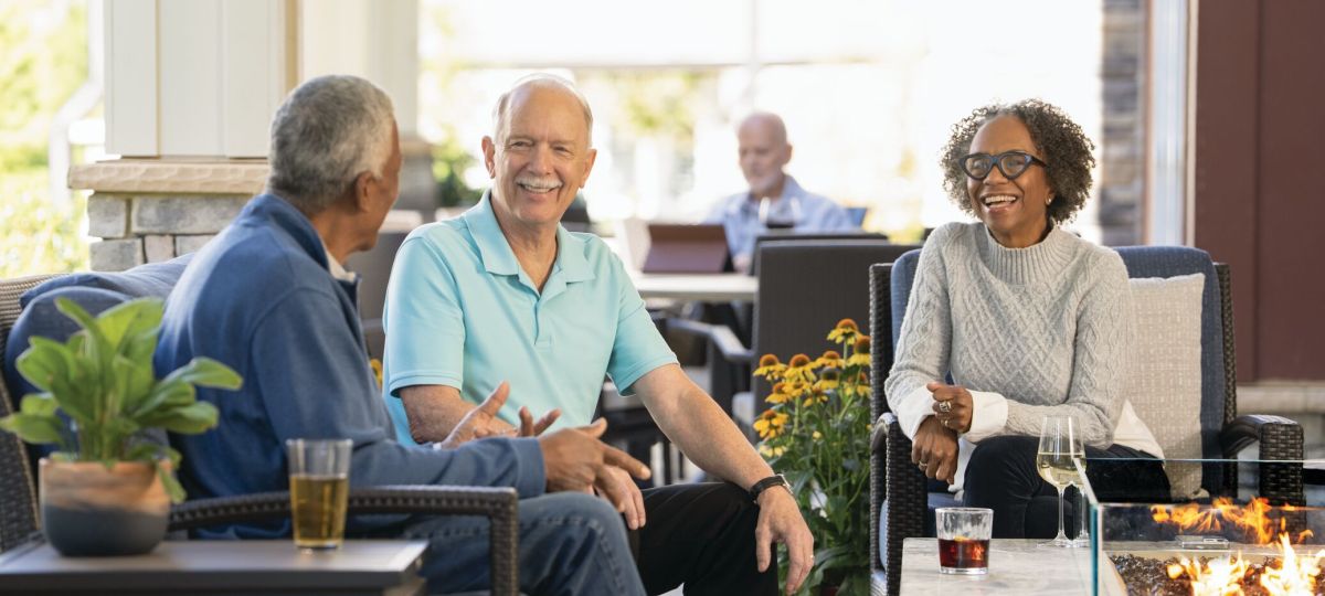 three seniors sitting together in a well-lit room, talking and smiling to each other