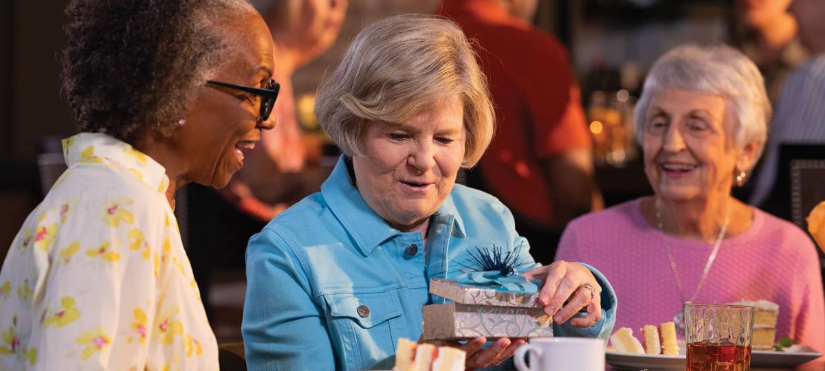 3 Residents having a conversation and opening a gift in a restaurant 