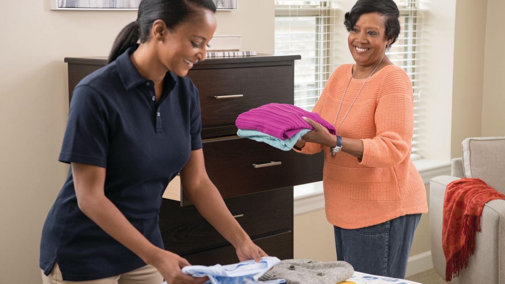 An Erickson Senior Living caregiver assisting a resident with folding and putting away laundry.