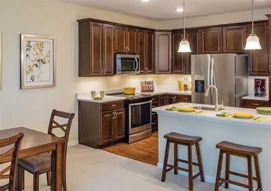 Interior shot of a spacious kitchen with bar seating and dining area inside of an Erickson Apartment home.