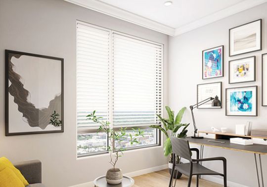 Spacious, bright den with a couch and desk and chair in an Erickson deluxe two-bedroom apartment.
