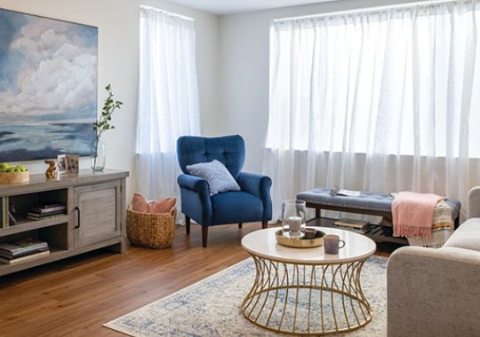 Cozy den with plush armchairs, entertainment unit, and large window letting in natural light - designed for comfort and relaxation in an Erickson apartment.