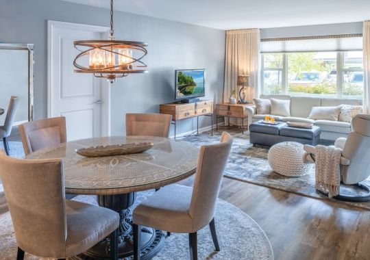Elegant open-concept dining and living room with modern lighting, wood flooring, and large windows.