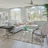 Living room with large windows, couch, ceiling fan, chair and table.