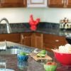 Close-up shot of a modern kitchen counter with a large red bowl full of delicious looking tortilla chips, a cutting board with sliced limes and a small bowl of red salsa.