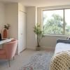 Cozy den with plush armchair, desk and chair, and large window letting in natural light - designed for comfort and relaxation in an Erickson apartment.