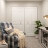 Cozy den with plush armchair and footstool, television sitting on top of an entertainment unit, and large double doors - designed for comfort and relaxation in an Erickson apartment.