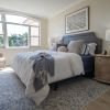 Cozy and spacious main bedroom with a large bed and open window inside of an Erickson Senior Living community apartment.