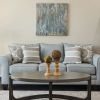 Close-up shot of a modern sofa and wall paintings and bookcase in a spacious Erickson apartment living room.