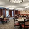 Spacious dining room with multiple tables, patterned chairs, large modern light fixtures, and decorative wall accents.