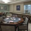 Game room with a poker table set with cards, additional seating, and a long shuffleboard table near a large window.