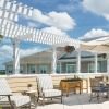 Outdoor rooftop patio with lounge chairs, umbrella‑shaded seating, hanging plants, and pergola-style overhead beams.