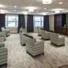 Theater-style lounge with patterned armchairs facing a large wall‑mounted TV and built‑in wooden cabinetry.