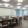 Creative activity room with multiple tables, art supplies, musical instruments, and large windows along one wall.